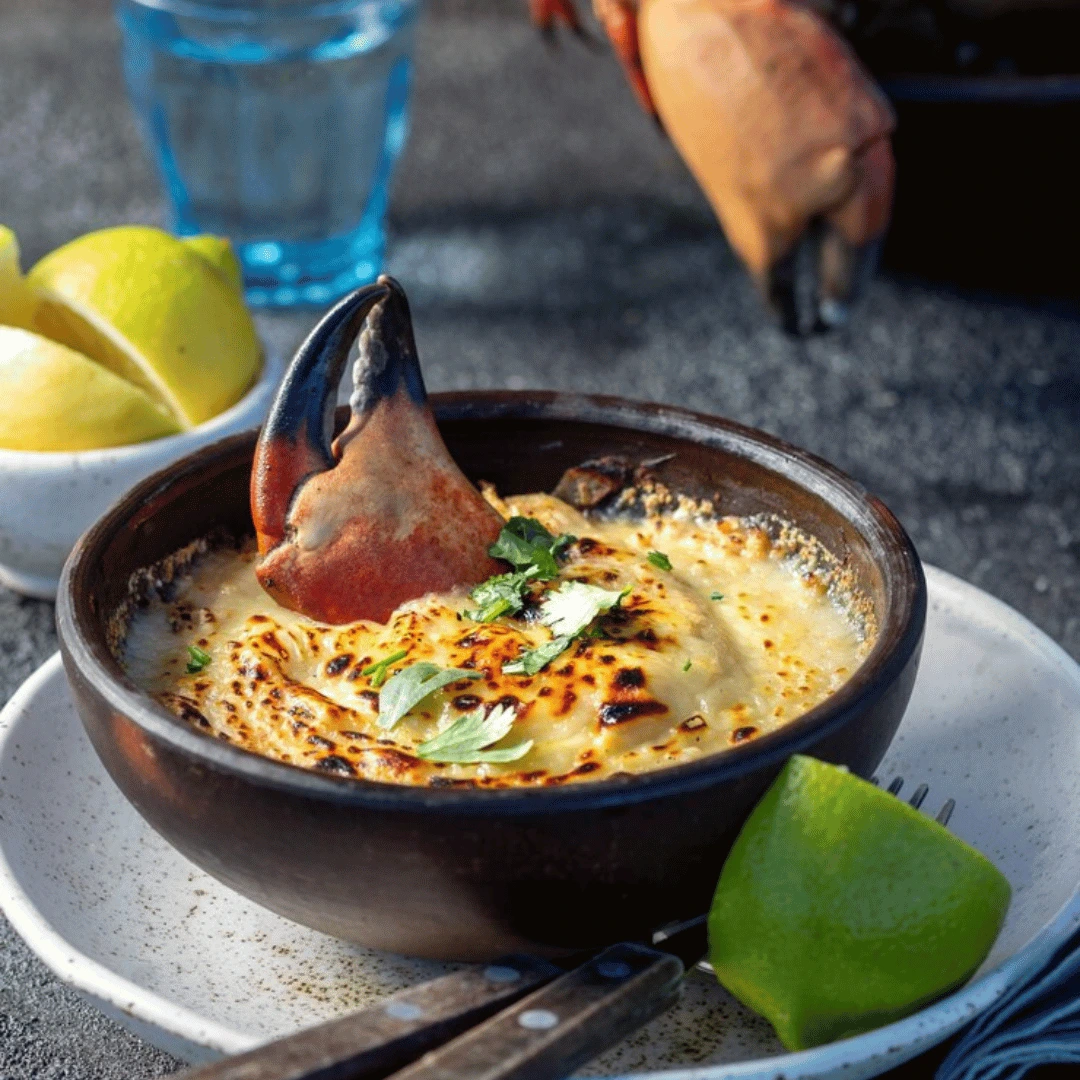 Plated crab brulee recipe with caramelized crust, garnished with herbs and served in a ramekin